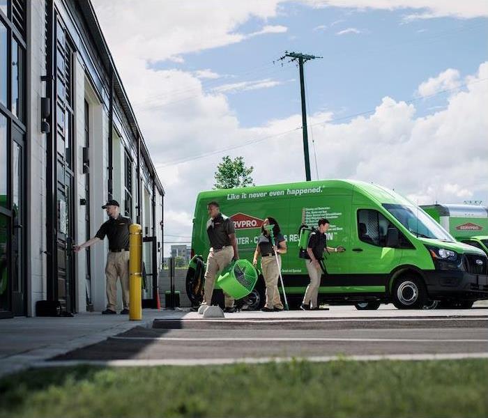 team of servpro workers unloading a branded work van and entering a business for a commercial job